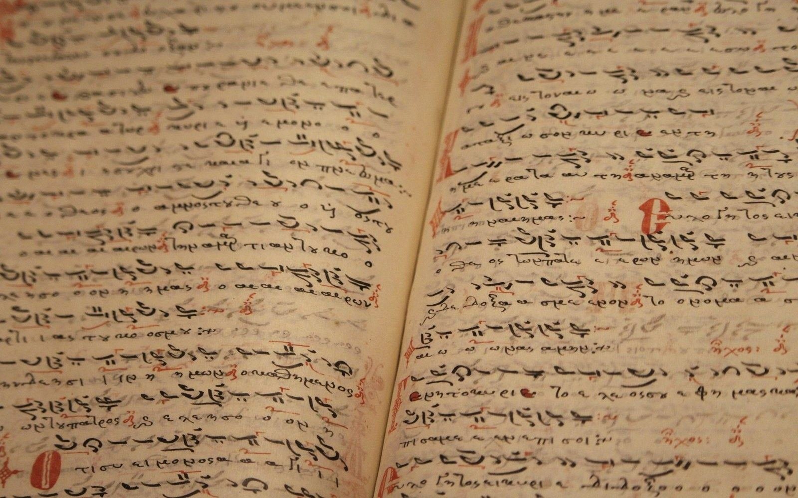 Open manuscript pages of handwritten Greek text with red and black ink annotations